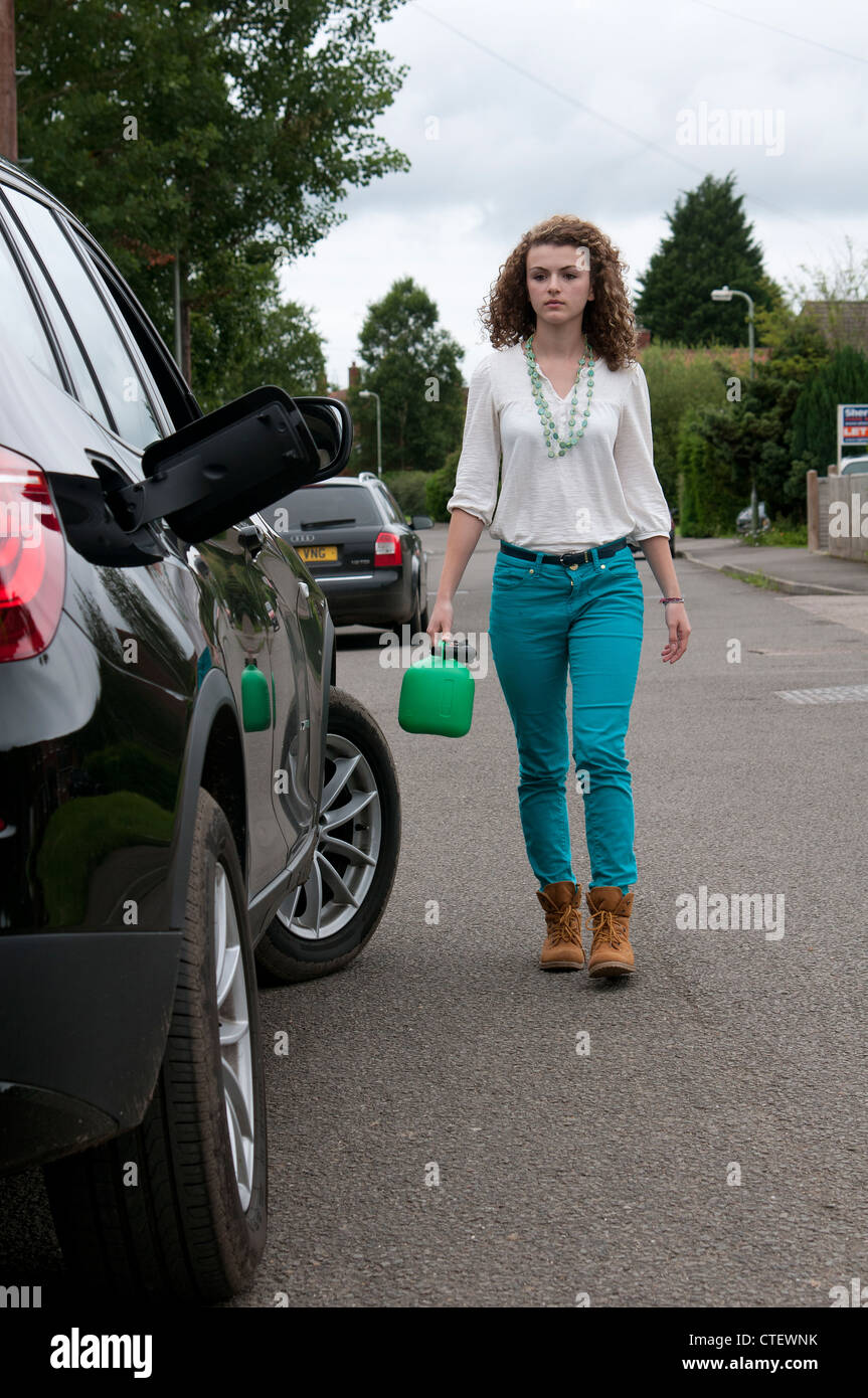 Giovani femmine automobilista a piedi con una plastica verde carburante benzina per raccogliere il combustibile Foto Stock