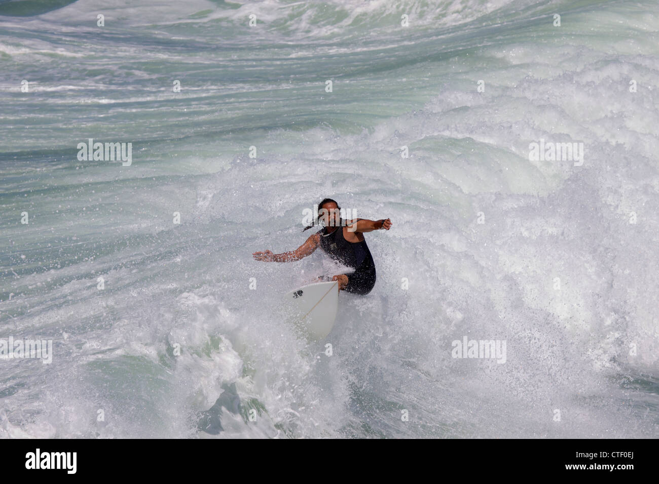 Un uomo surf a Huntington Beach pier California circondato con acqua bianca come la forma d'onda si rompe intorno a lui Foto Stock