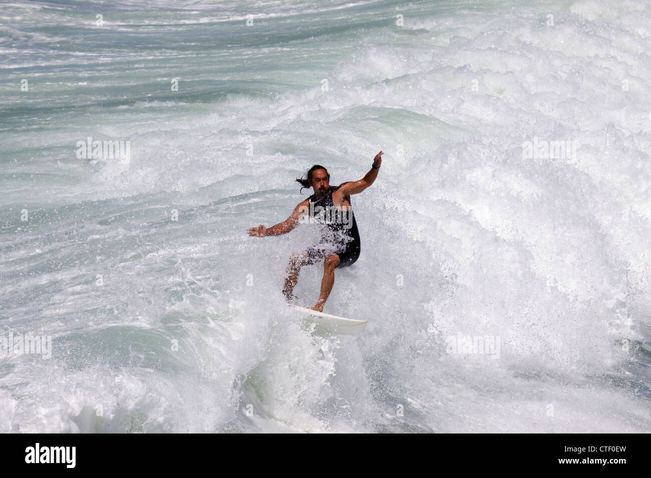 Un uomo surf a Huntington Beach pier California circondato con acqua bianca come la forma d'onda si rompe intorno a lui Foto Stock