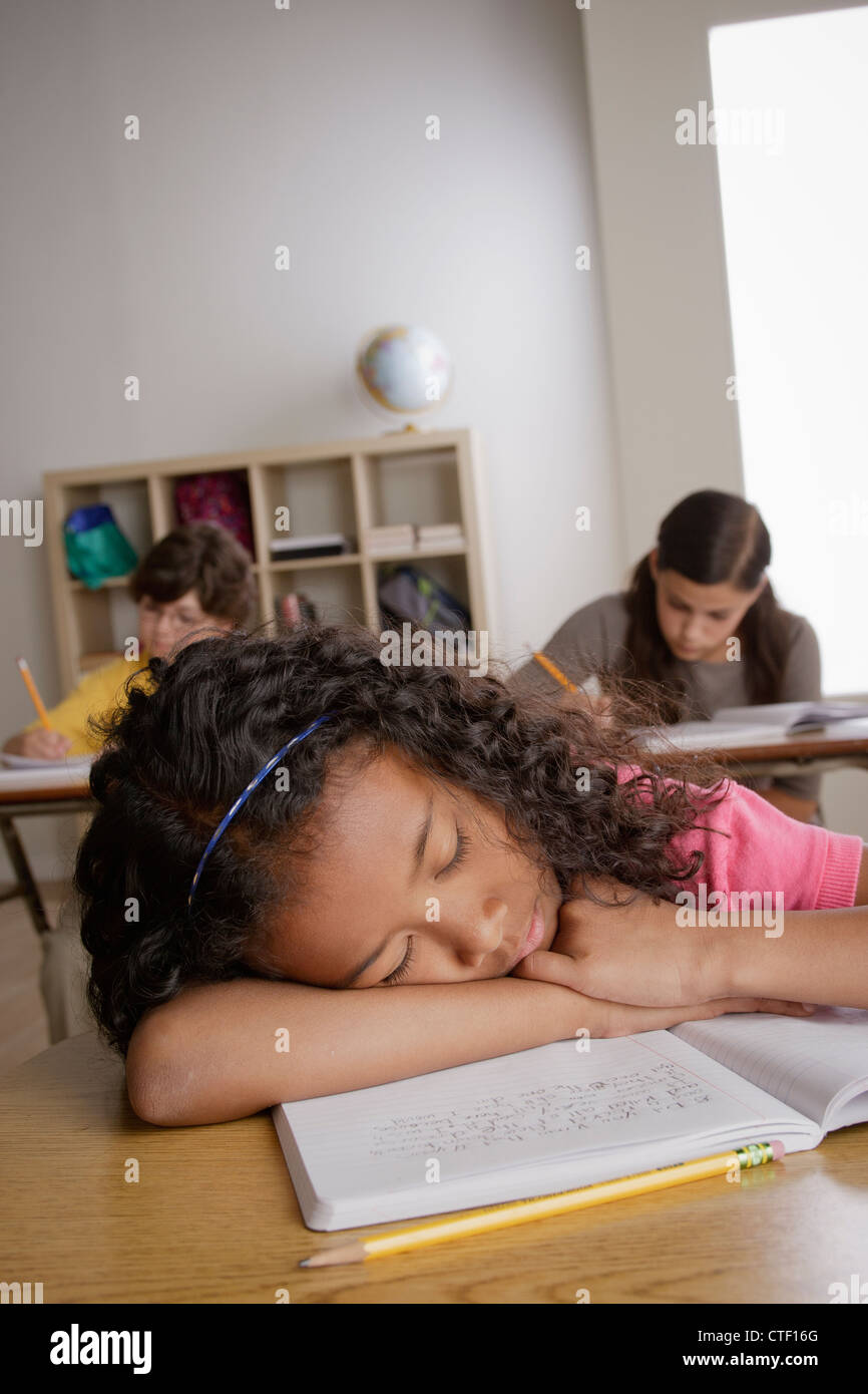 Stati Uniti, California, Los Angeles, ragazza (10-11) a sonnecchiare sulla scrivania con la ragazza (12-13) e ragazzo (10-11) in background Foto Stock