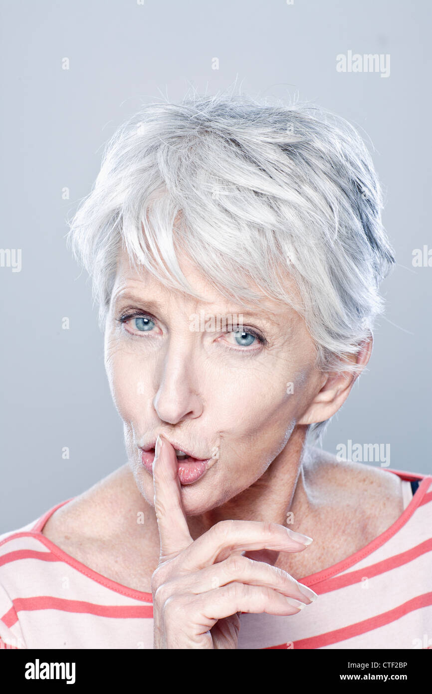 Ritratto di donna senior con il dito sulle labbra, studio shot Foto Stock