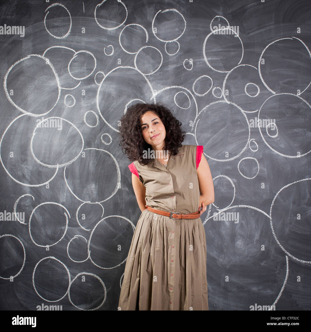 Giovane insegnante in posa contro la lavagna con bolle scritto in Chalk Foto Stock