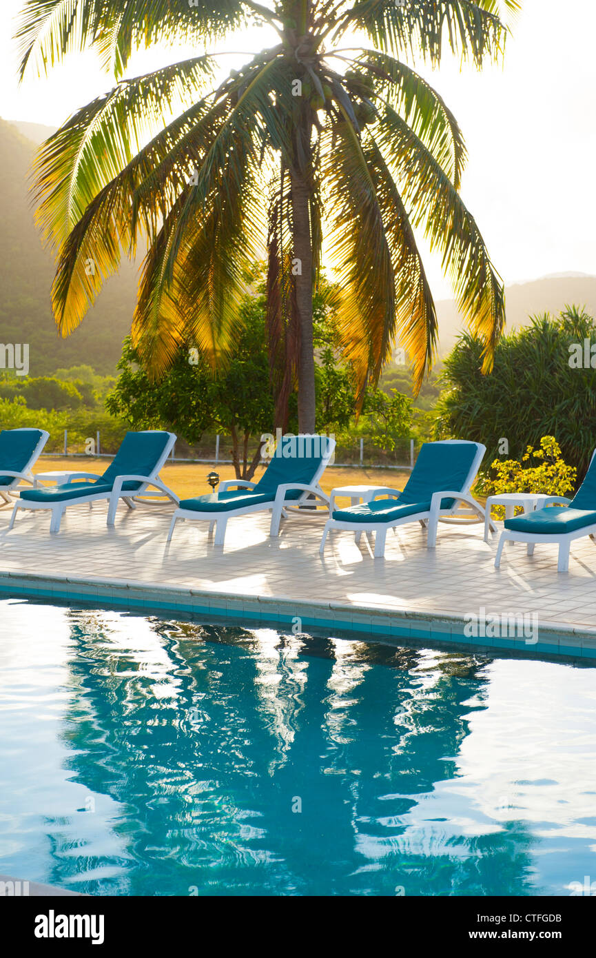 Caribbean West Indies Nevis Mount Nevis Hotel piscina relax tropicale sedie a sdraio al tramonto attraverso le palme Foto Stock