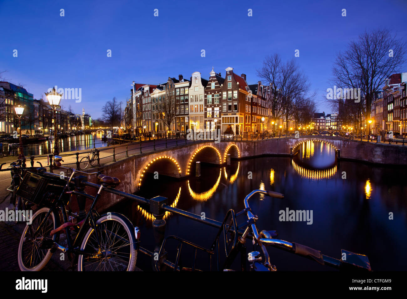 Amsterdam, crepuscolo, attraversamento di canali chiamati Keizersgracht en Leidsegracht. Ponti illuminati, biciclette. UNESCO - Sito Patrimonio dell'umanità. Foto Stock