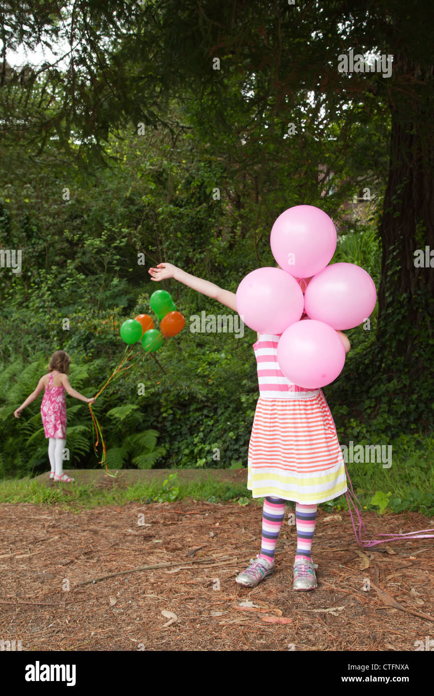 Una bambina in abito a strisce è in possesso di palloncini rosa. Foto Stock