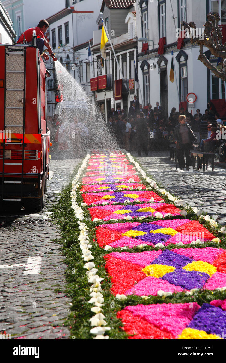 Camion dei pompieri spruzzare acqua sul tappeto di fiori durante la festa religiosa a Ponta Delgada, isole Azzorre. Foto Stock