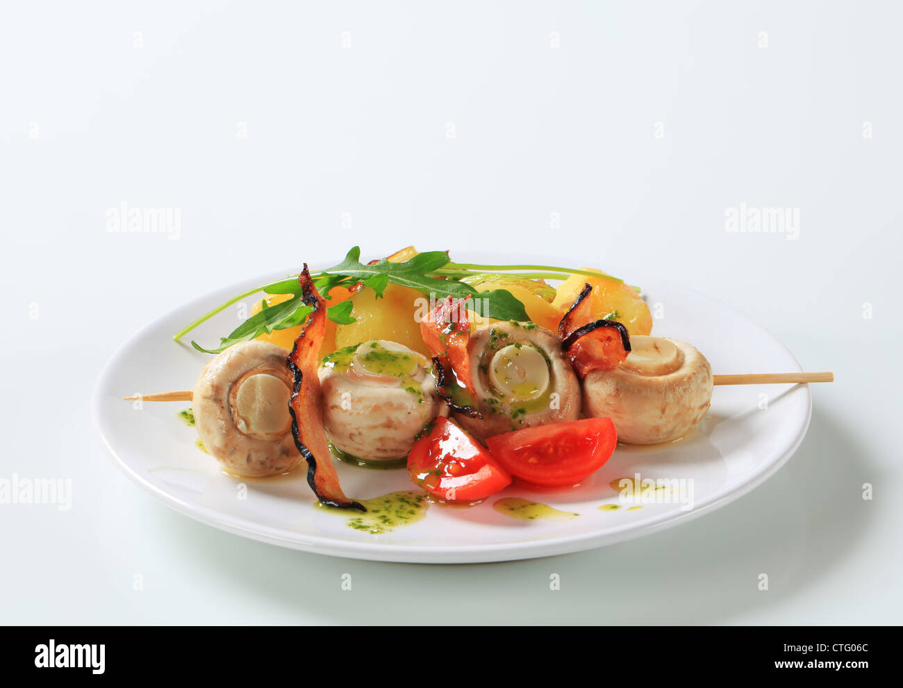 Spiedino di funghi champignon con pancetta croccante e patate Foto Stock