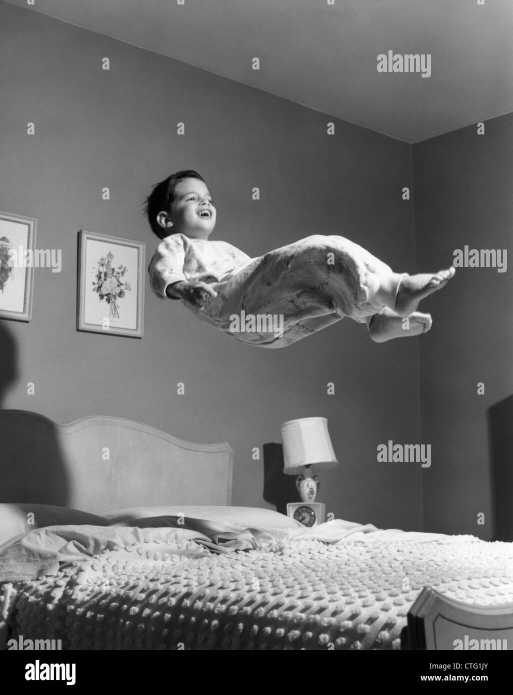 Anni Cinquanta BOY in pigiama elevato sopra il letto Foto Stock
