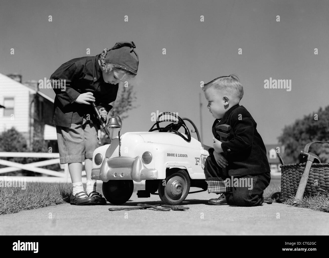Degli anni cinquanta un ragazzo e una ragazza A GIOCARE A riparazione auto giocattolo Foto Stock