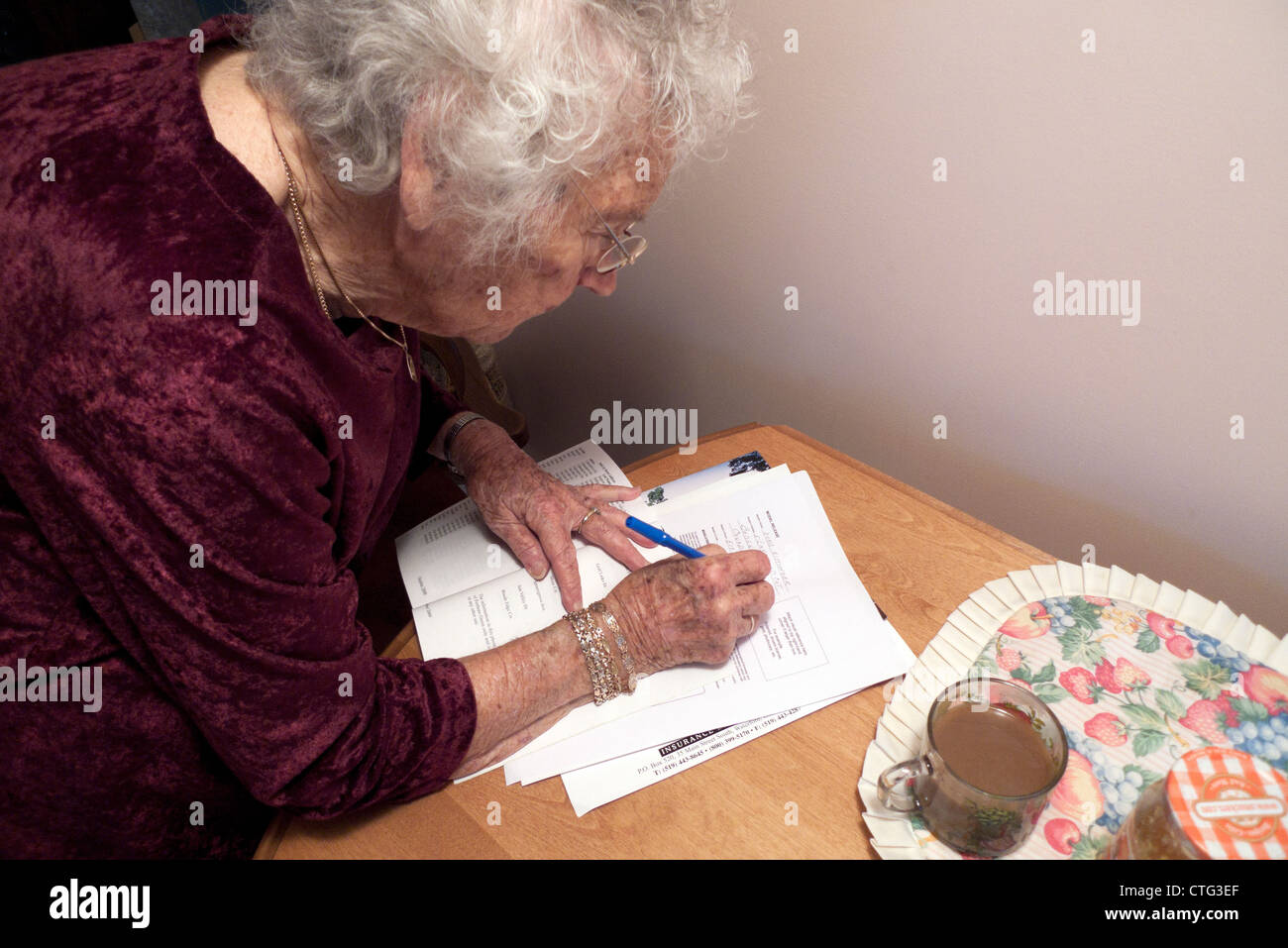 Donna anziana attiva, pensionata di età compresa tra i 90 anni, che firma documenti legali a casa in Canada, KATHY DEWITT Foto Stock
