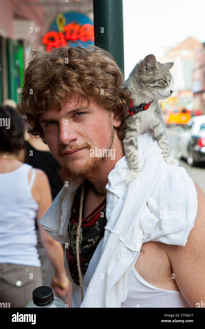 Giovane uomo a camminare con un gatto sulla sua spalla nel Quartiere Francese di New Orleans, LA Foto Stock