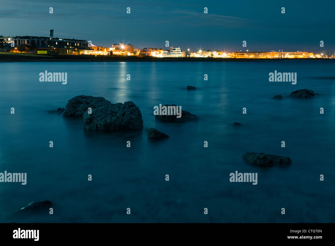 La riflessione della città sul mare di notte Foto Stock