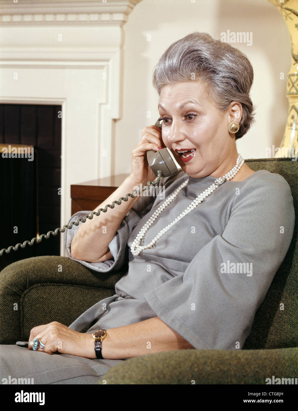 Anni sessanta SENIOR DONNA CHE PARLA eccitato espressione facciale sul retro del telefono Foto Stock