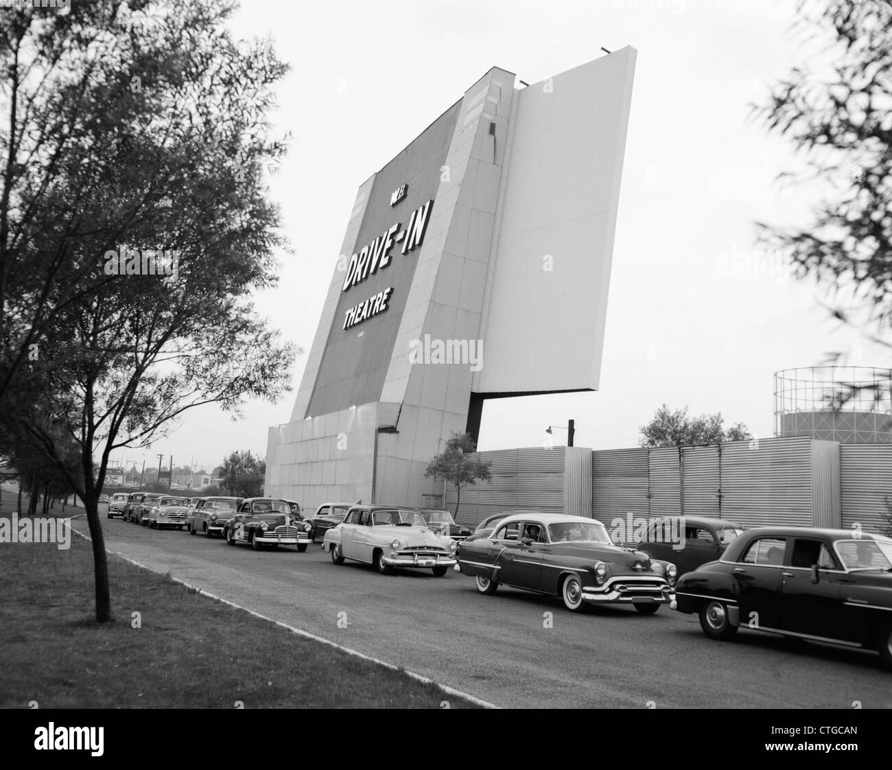 Anni Cinquanta automobili NEL TRAFFICO lasciando entrare drive-in Theatre Foto Stock
