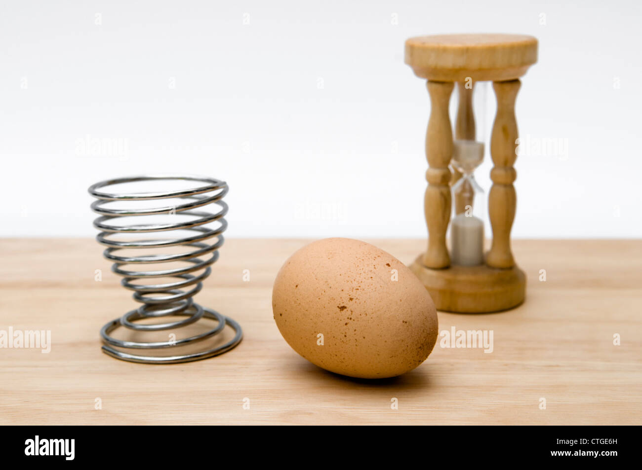 Still Life studio shot di clessidra, uovo uovo e cup sul tagliere di legno contro uno sfondo bianco Foto Stock