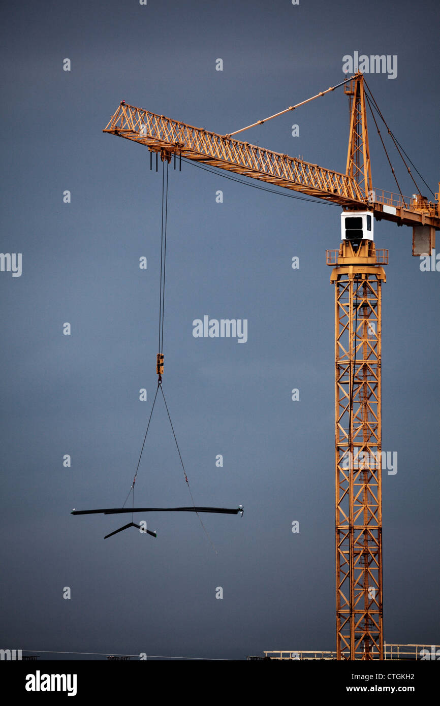 Giallo gru a torre in movimento lungo un carico di acciaio. Foto Stock