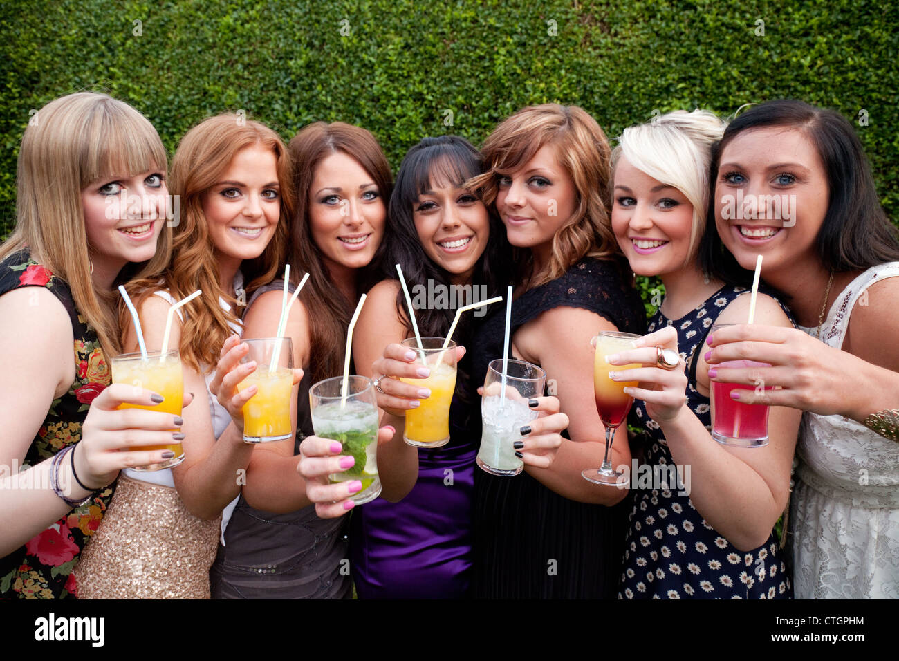 Un gruppo di sette giovani donne godendo di bere alcol cocktail in un party, REGNO UNITO Foto Stock