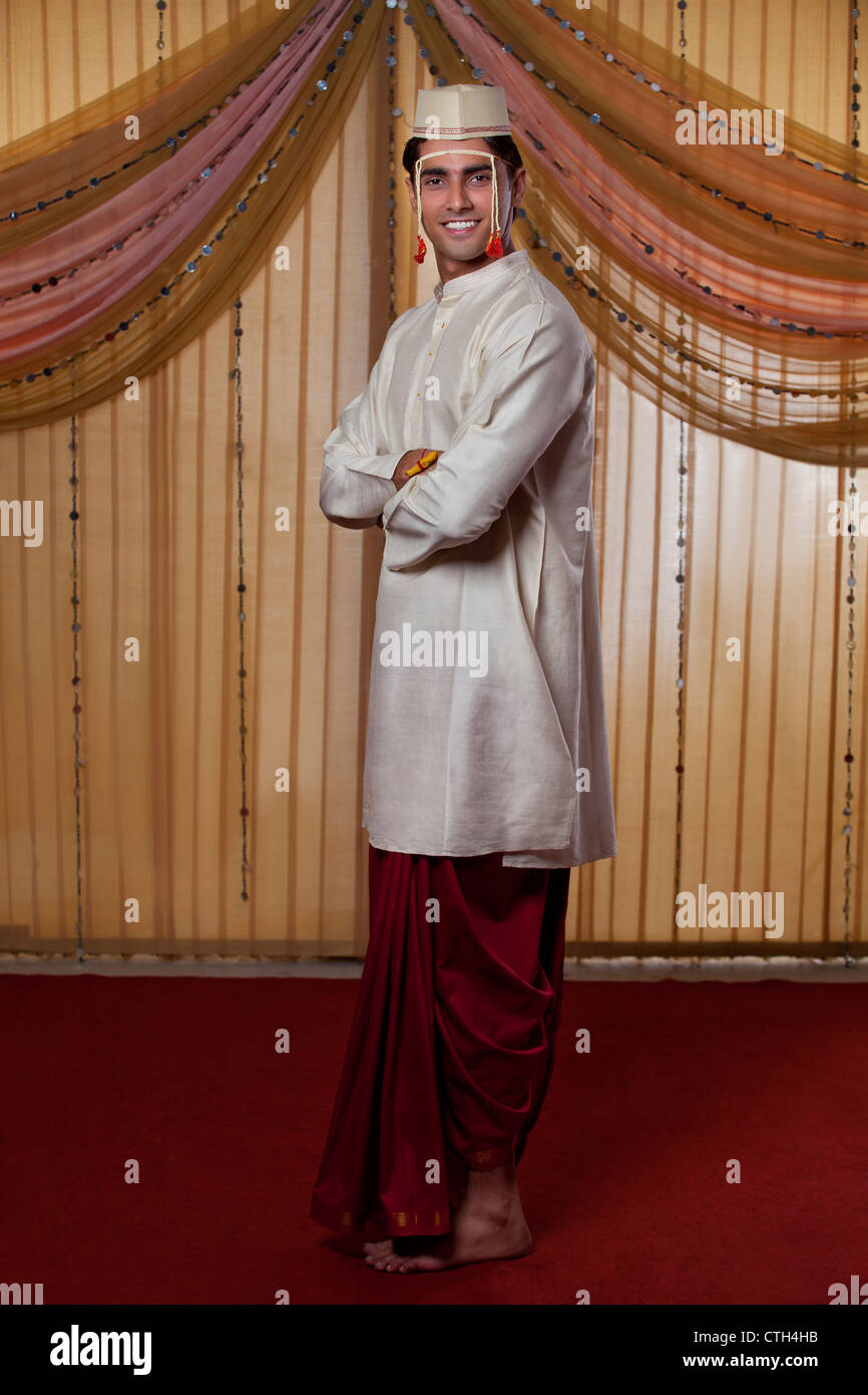Lunghezza completa di Indian groom sorridente con le braccia incrociate Foto Stock