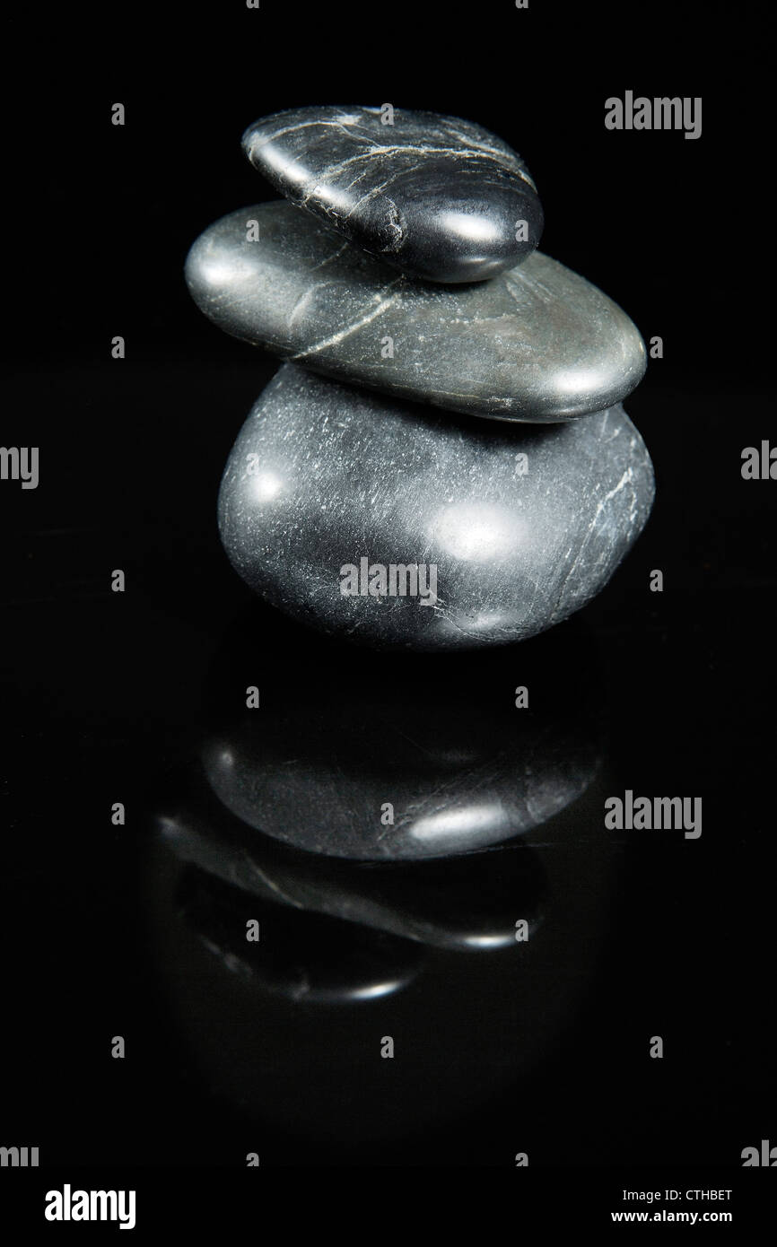 Trhee pietre impilate equilibrato isolati su sfondo nero. Foto Stock