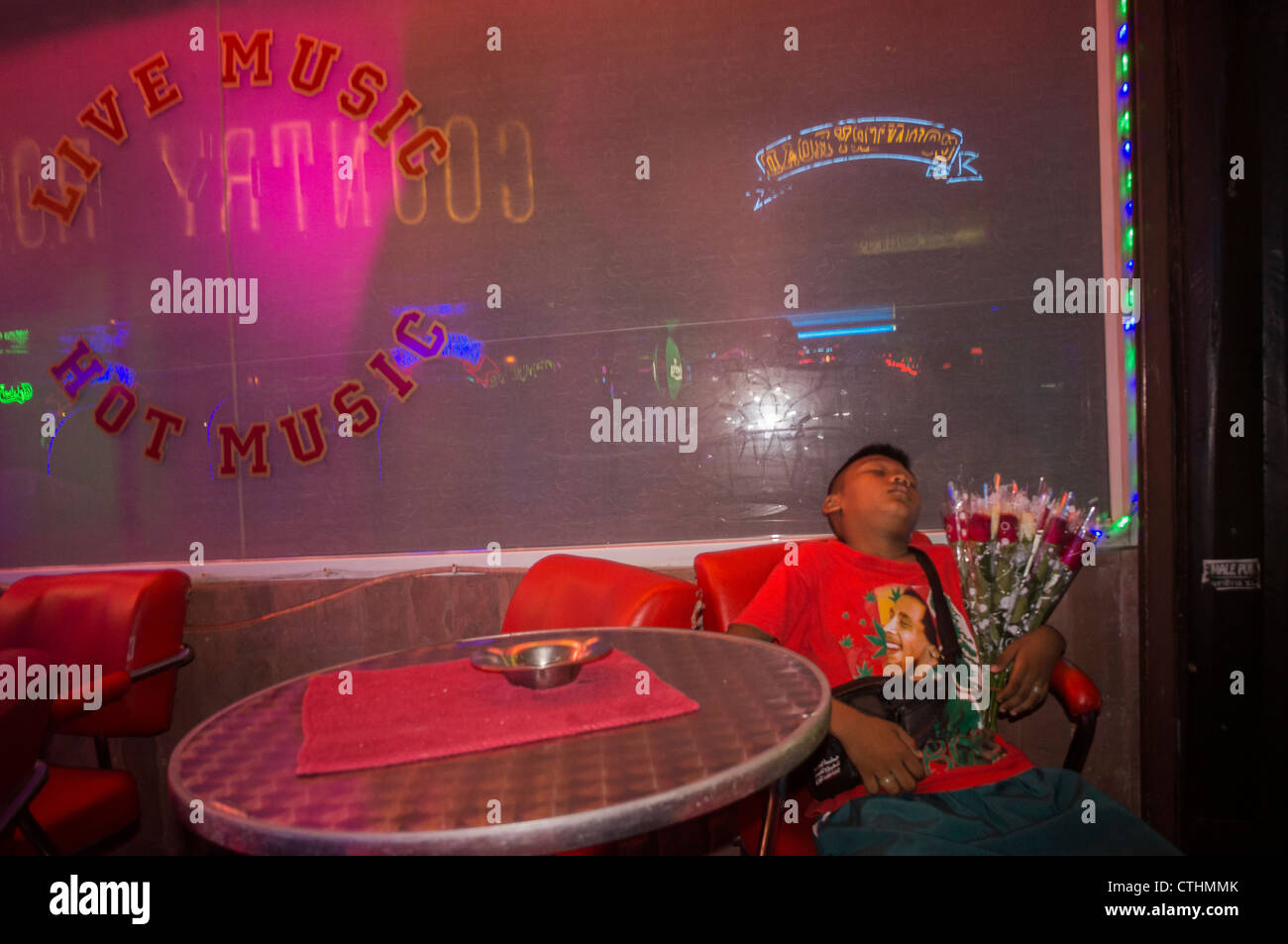 Street trader, bambino con fiori dormire nella parte anteriore del nightclub, Soi Cowboy, centro della vita notturna, bar, Bangkok, Thailandia Foto Stock