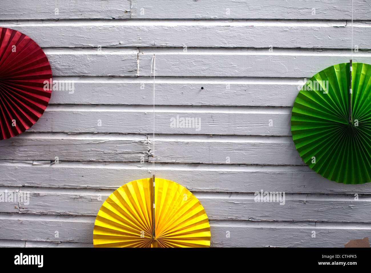 Tre ornamentali a forma di ventola cerchi di carta su una parete bianca. Foto Stock