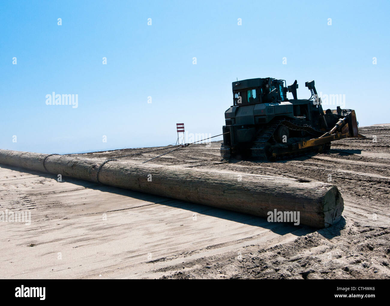 Operatore attrezzatura 2a Classe Chris Lindsey, assegnato a Amphibious Construction Battaglione (ACB) 1, utilizza un bulldozer per tirare un log per riparare la sabbia dopo l'operazione Brilliant Zenith. La spiaggia è stata utilizzata come zona di sosta per una strada rialzata galleggiante durante l'esercizio. I marinai dell'ACB-1 lavorarono per riportare la spiaggia alle sue condizioni originali. Foto Stock