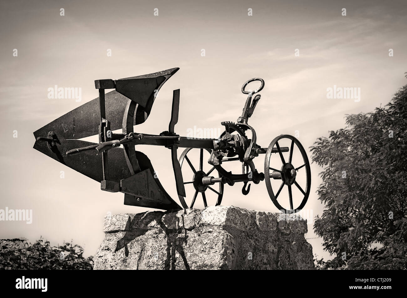 Monumento omaggio nella piazza di una città di Burgos al vecchio aratro di ruote e scarica sul suo piedistallo di pietra, Castiglia e Leon, Spagna, Europa. Foto Stock