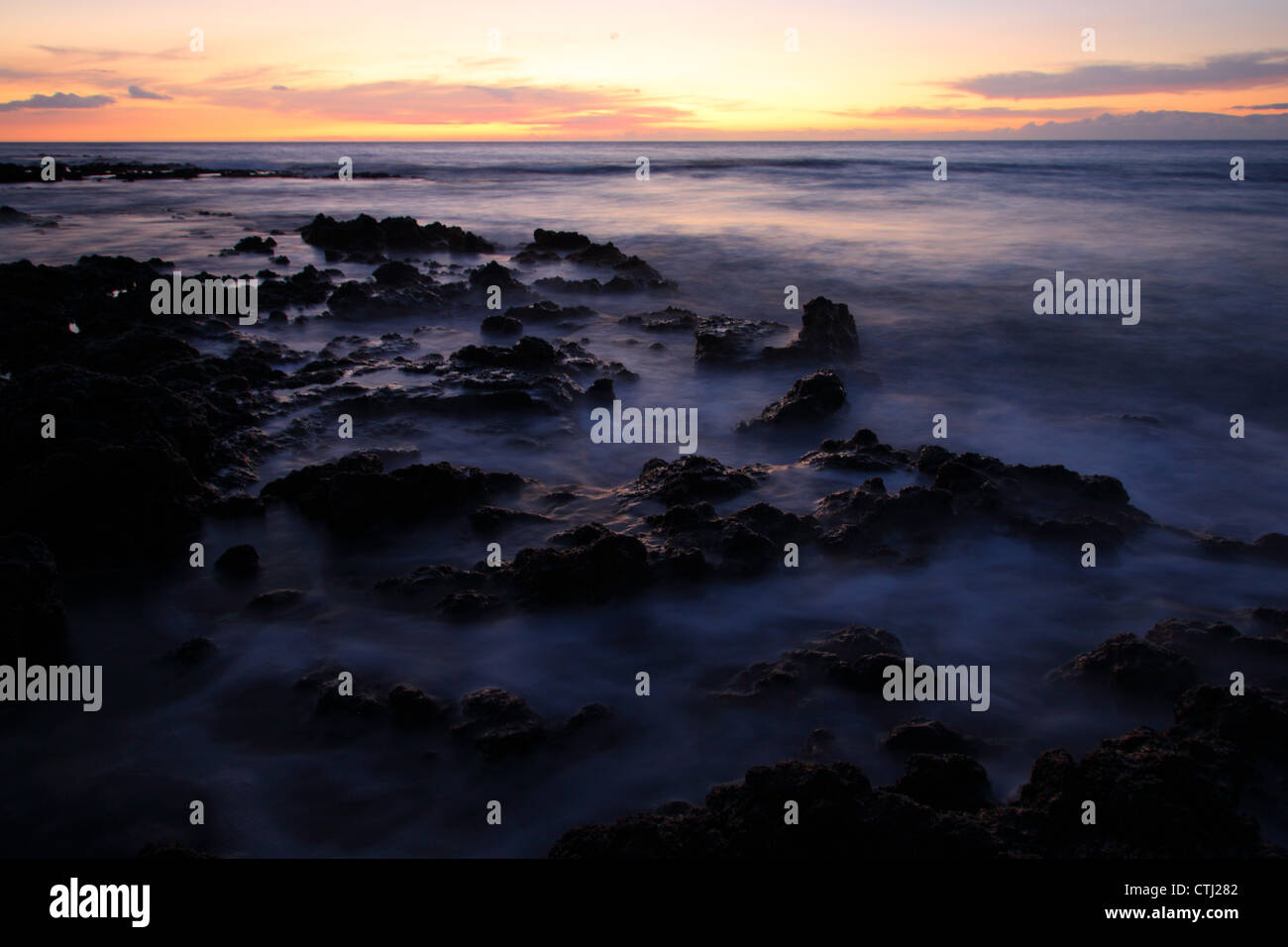 Costa rocciosa al tramonto, Hawaii Foto Stock