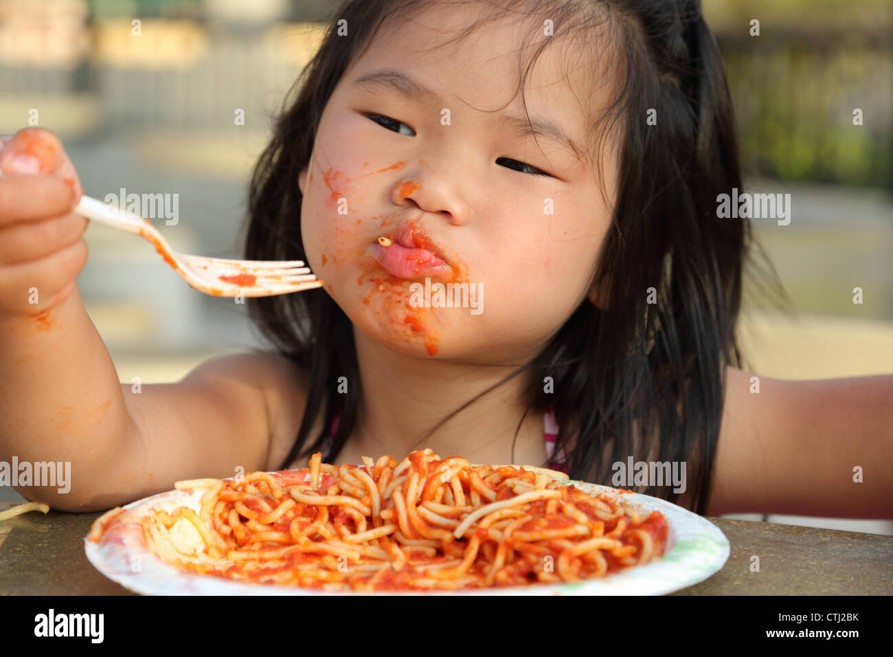 Ragazza giovane mangiare spaghetti e rendendo il disordine Foto Stock