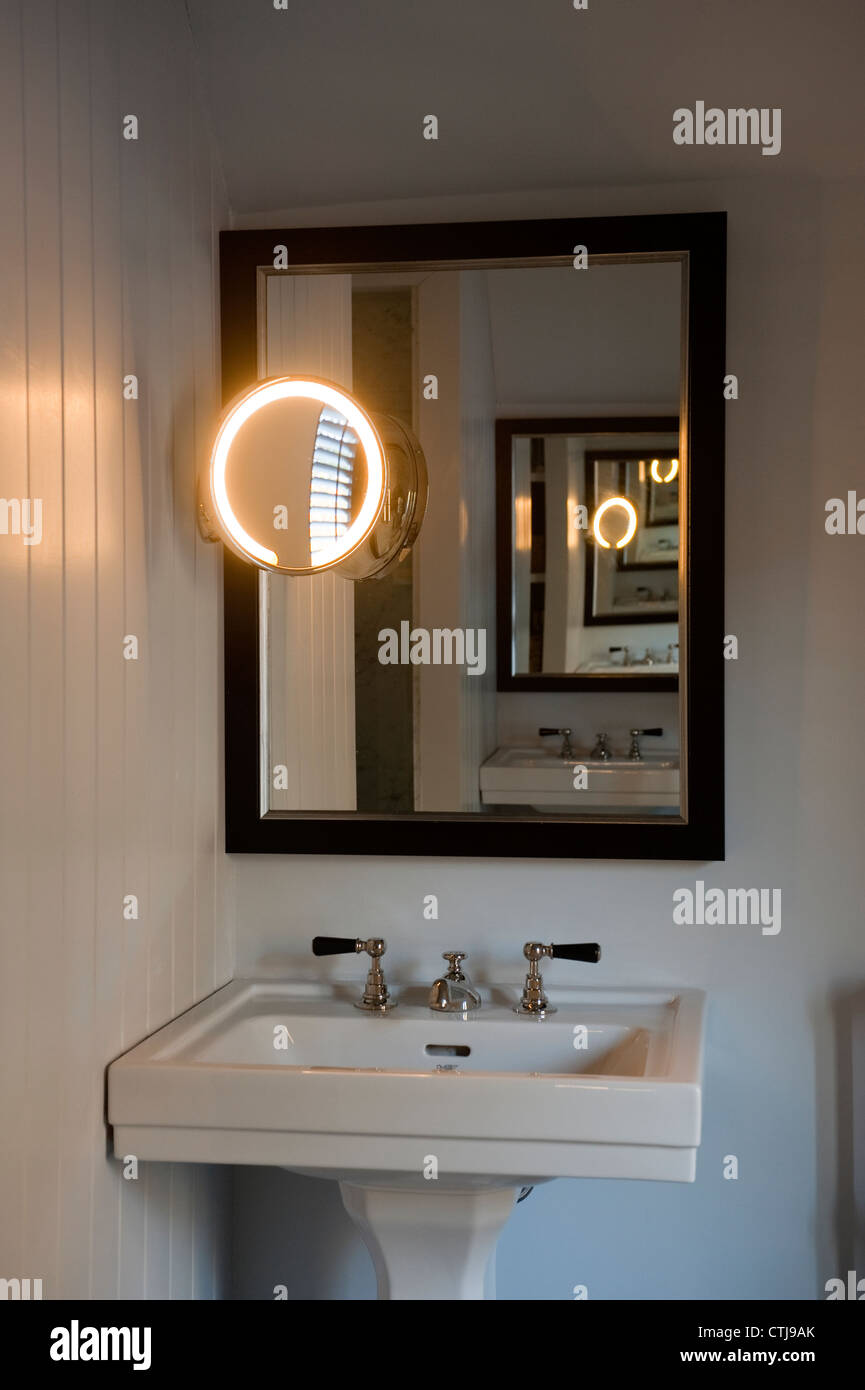Lavandino Con nickle rubinetti e nickle circolare di specchietto di cortesia illuminato Foto Stock