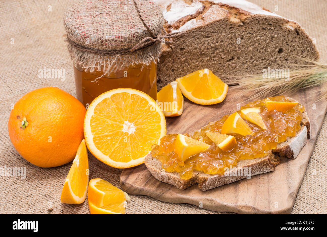Pane con marmellata di arancio e frutta fresca su sfondo rustico Foto Stock