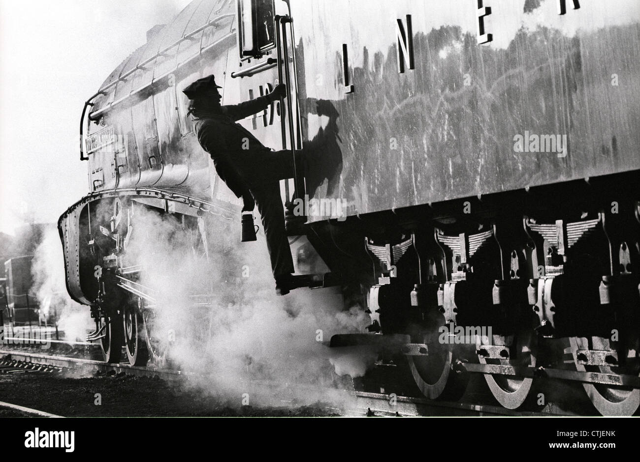 Un autista di salite a bordo di Londra nord-orientale della ferrovia (lner) gresley classe a4 locomotiva a vapore numero 4498 chiamato dopo il suo designer 'sir nigel gresley.' Le conserve di locomotiva a vapore era sulla grande stazione ferroviaria centrale a Loughborough. il conducente sta tenendo il suo smalto tè può per il viaggio. Foto Stock