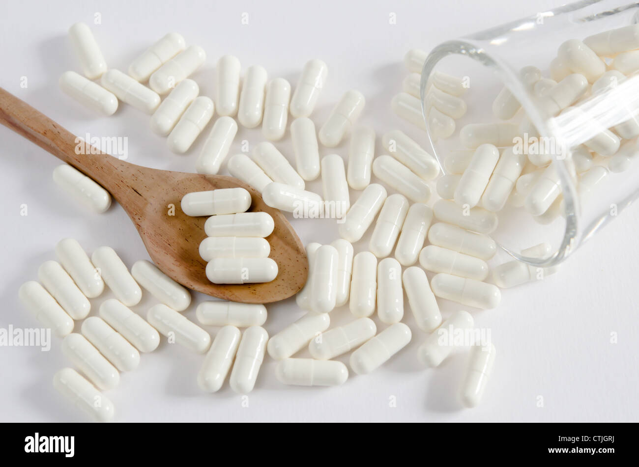 Pillole di bianco la fuoriuscita di vetro e pillole sul cucchiaio Foto Stock