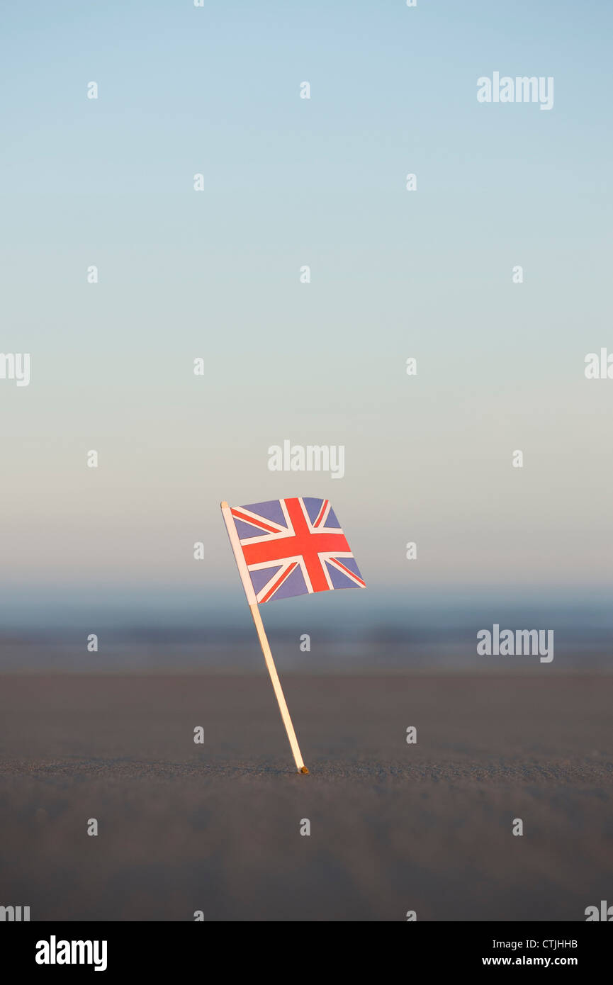 Union Jack flag bloccato in una spiaggia a sunrise. Messa a fuoco selettiva Foto Stock