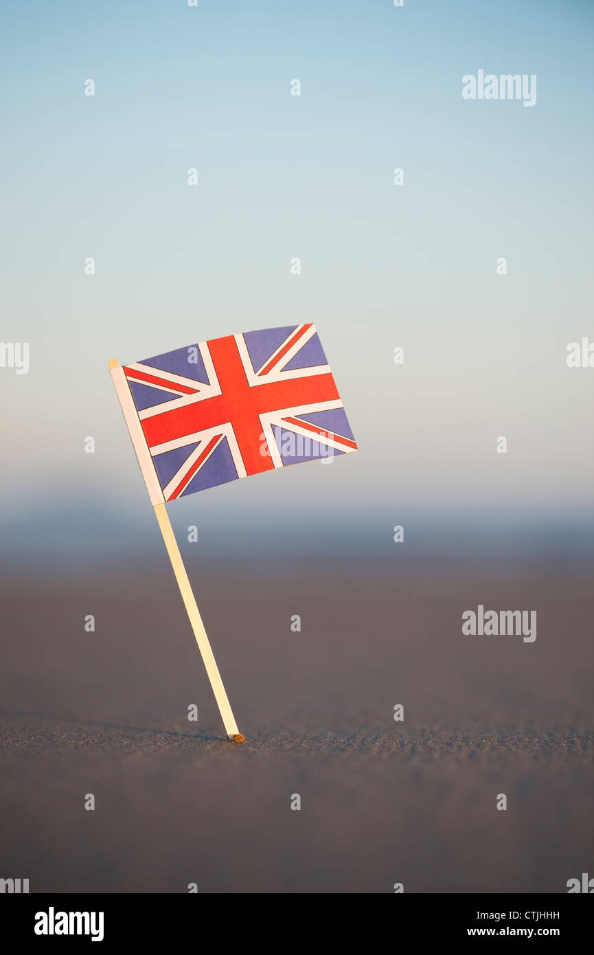 Union Jack flag bloccato in una spiaggia a sunrise. Messa a fuoco selettiva Foto Stock