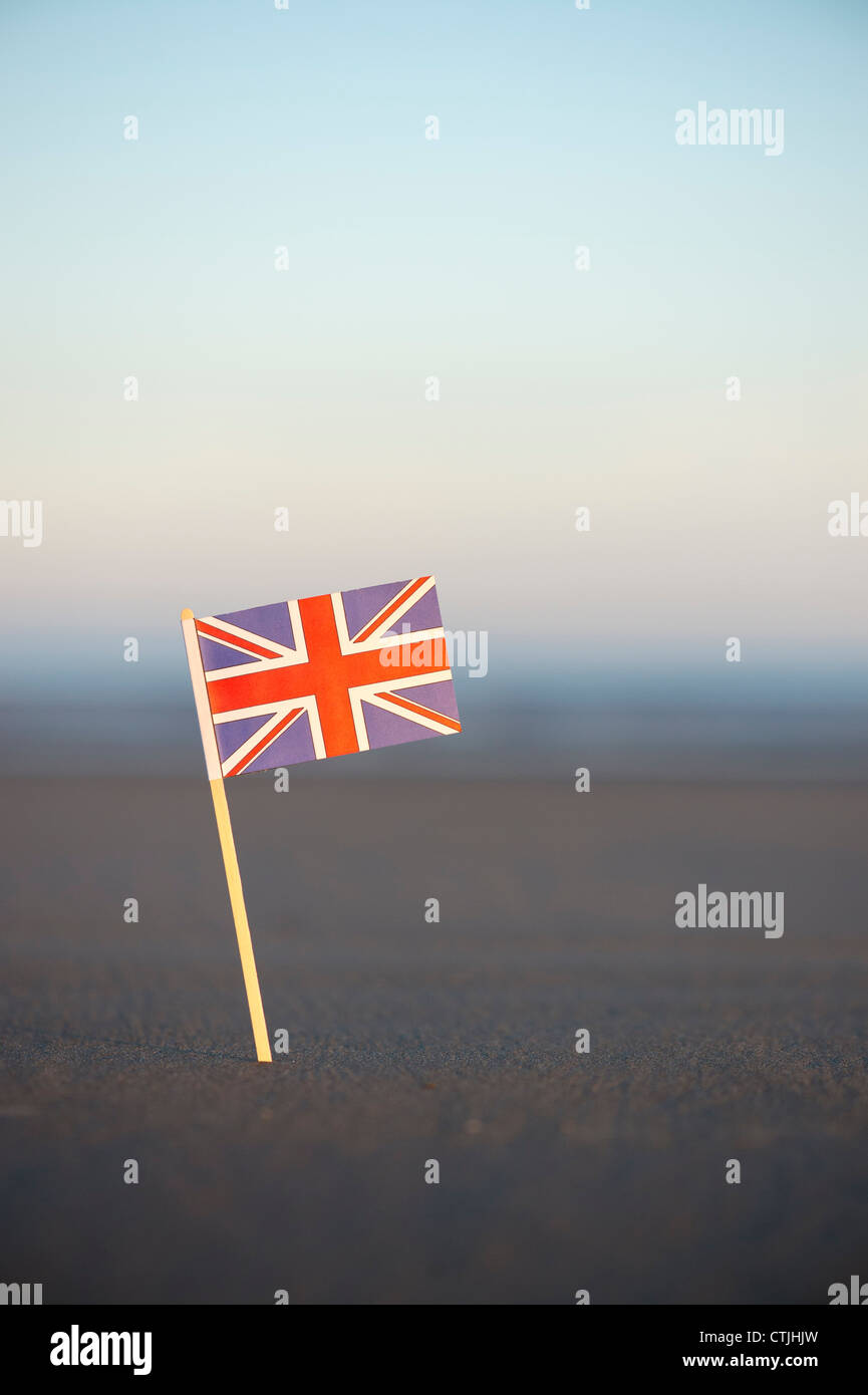 Union Jack flag bloccato in una spiaggia a sunrise. Messa a fuoco selettiva Foto Stock