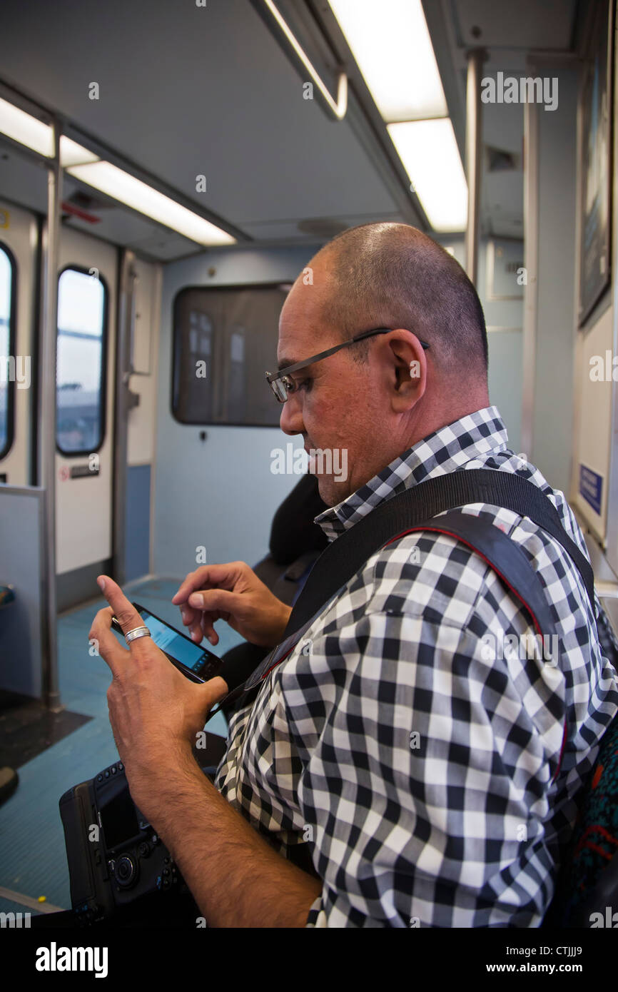 Los Angeles, California - Un motociclista su Los Angeles Metro rail sistema utilizza un telefono intelligente. Foto Stock