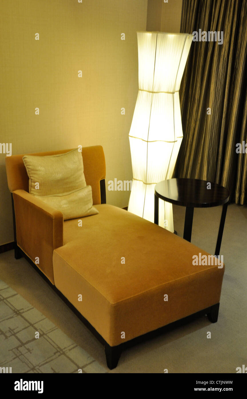 Un divano vuoto in un hotel di lusso con una luce accanto a Foto Stock
