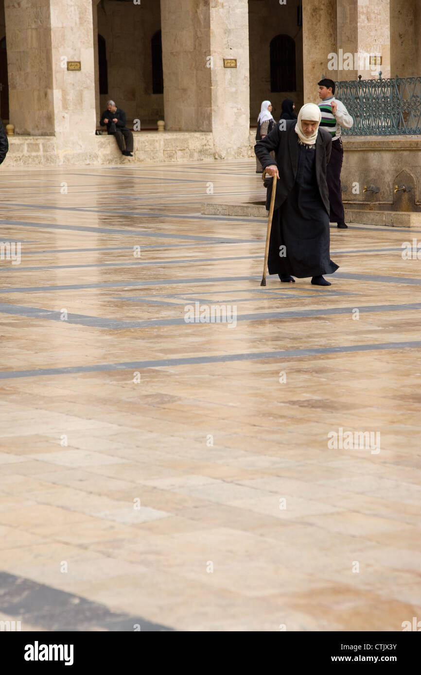 Il vecchio uomo che cammina sul pavimento durante la preghiera presso la grande moschea di Aleppo, Siria. Foto Stock