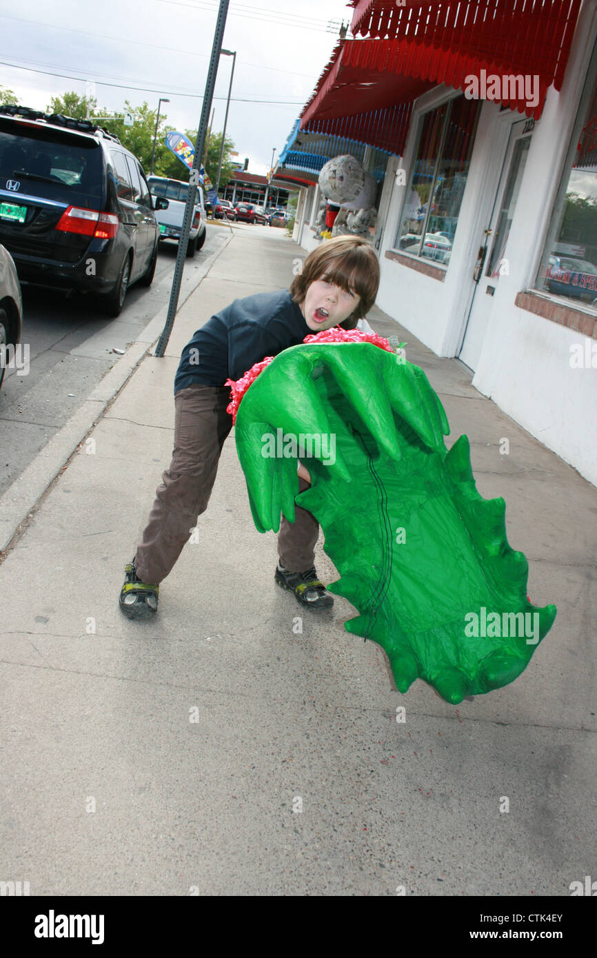 Bambino di otto anni tenendo un mostro gigante impianto Pinata per la sua festa di compleanno. Foto Stock