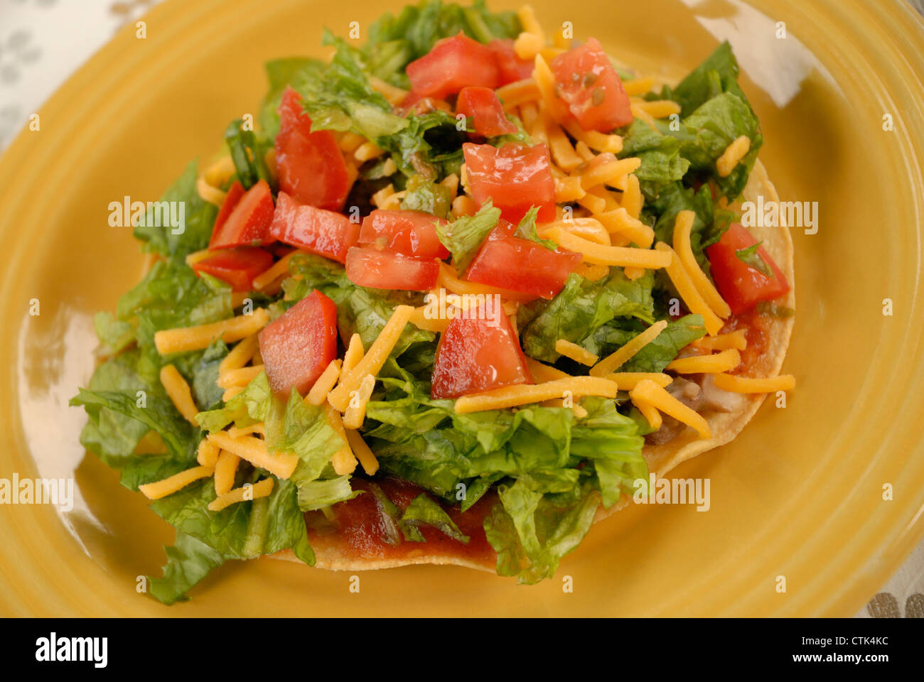 Tostada vegetariana; tortilla di mais e rabboccato con refried fagioli, lattuga, il formaggio e i pomodori, con salsa taco. Foto Stock