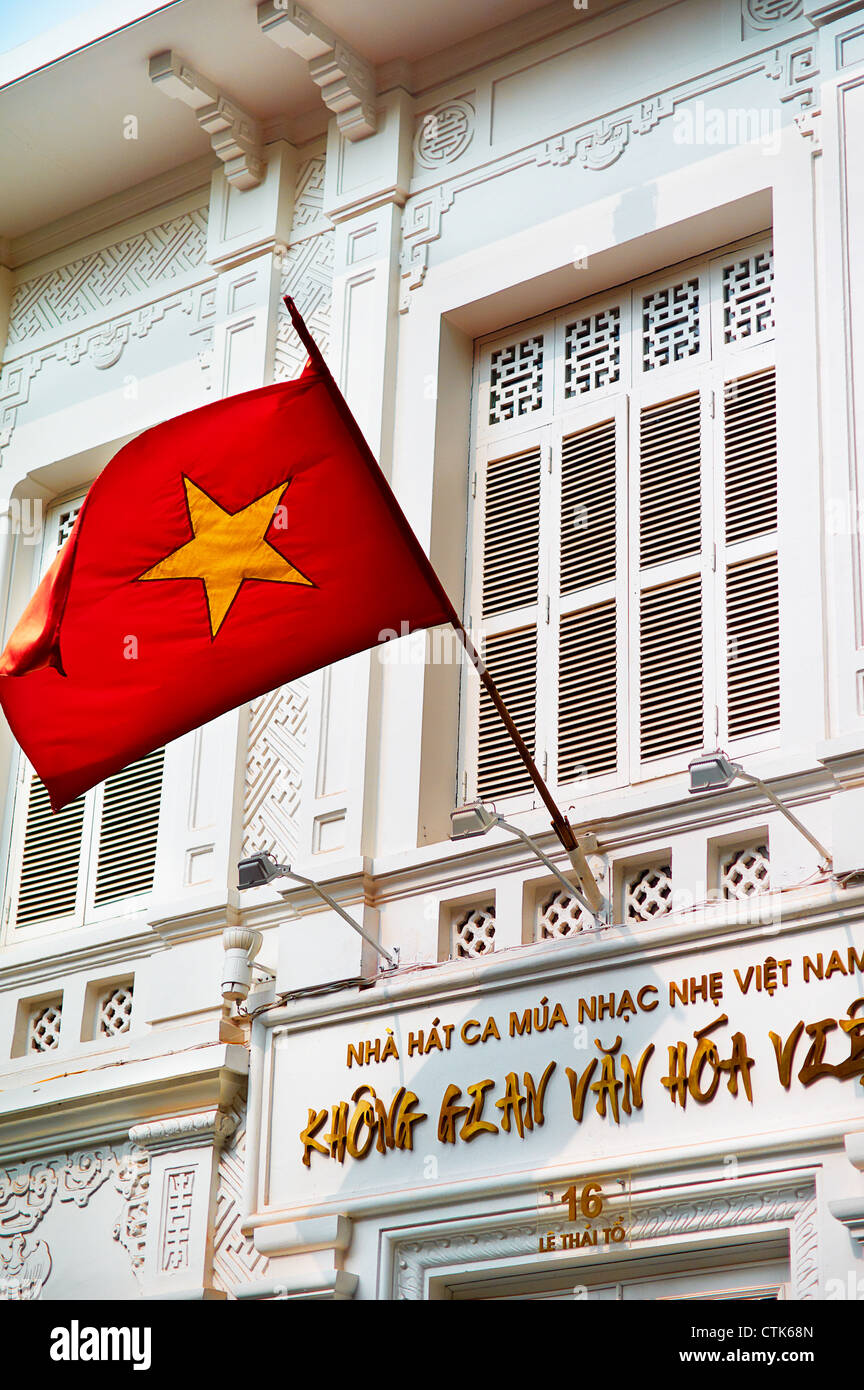 La bandiera del Vietnam, progettato nel 1940, sventolando nella parte anteriore di un passato coloniale francese edificio di stile. Foto Stock