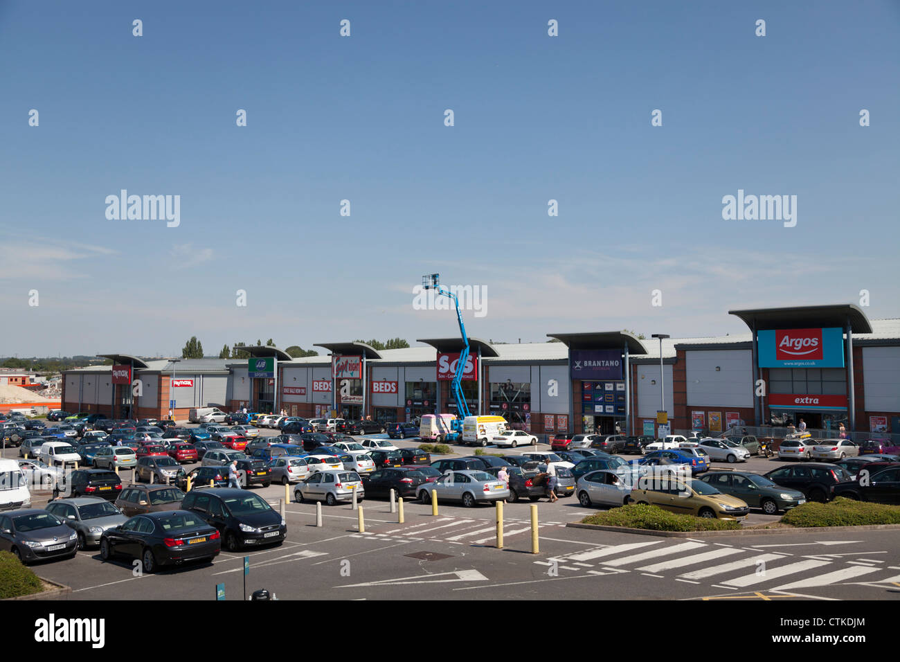 Vendita al dettaglio al di fuori del parco comunale con vari negozi e parcheggio auto Foto Stock