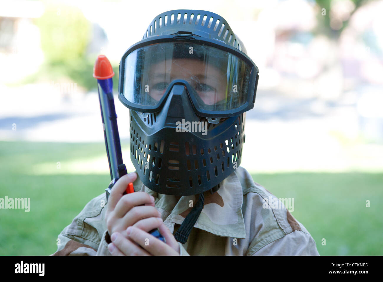 Ragazzo in possesso di una pistola giocattolo di indossare abbigliamento militare all'aperto, Stati Uniti. Foto Stock