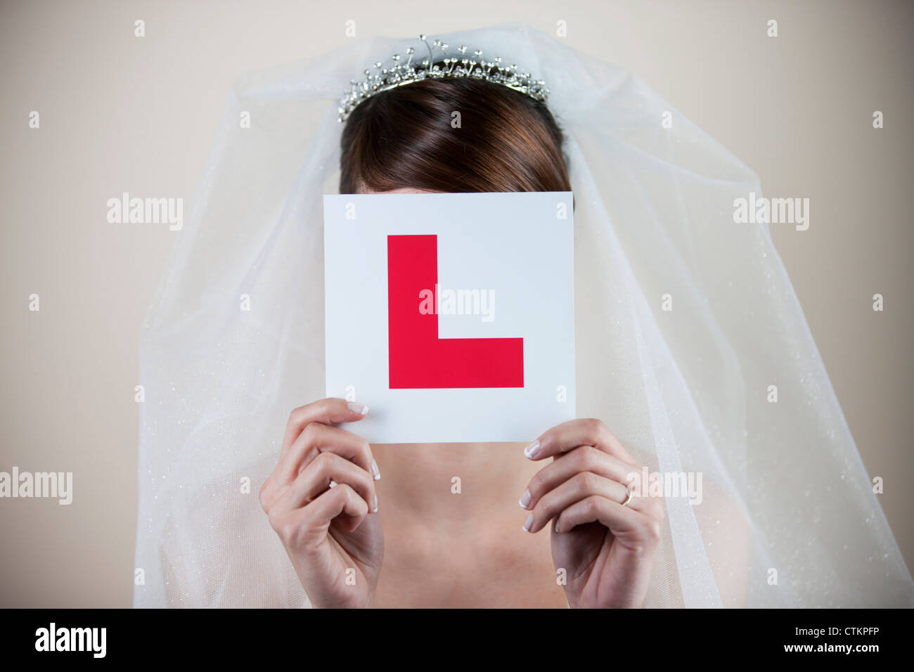 Una giovane sposa in possesso di un permesso di studente nella piastra anteriore del suo viso Foto Stock