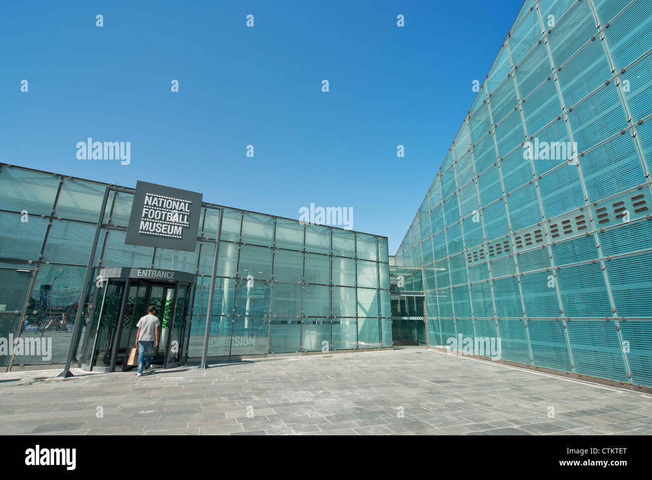 Un visitatore entra nel Museo Nazionale del Calcio (Urbis) in Manchester su una chiara soleggiata giornata estiva. Foto Stock