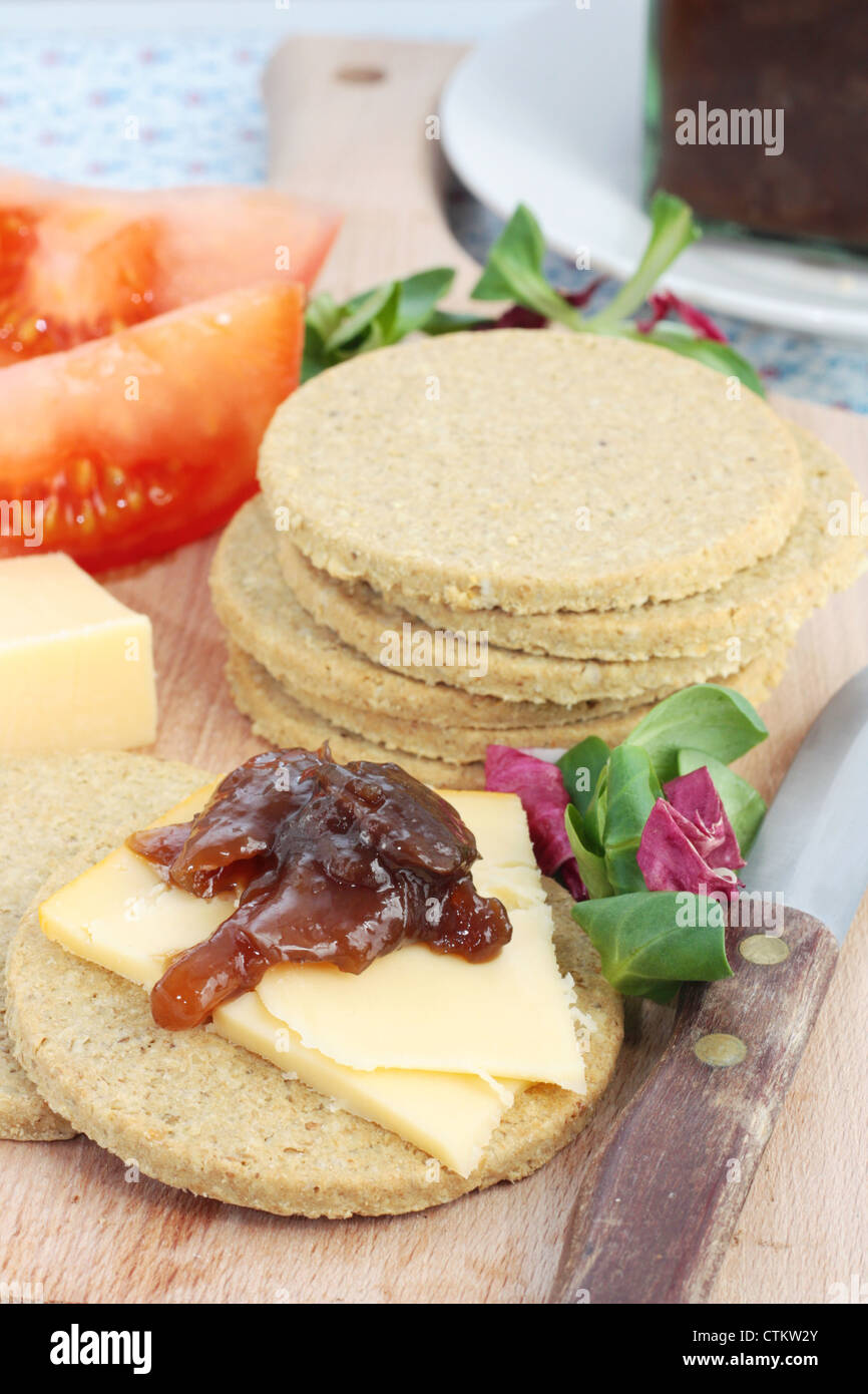 Oatcakes scozzese servito con il formaggio e cipolle caramellate chutney. Su di un tagliere di legno. Foto Stock