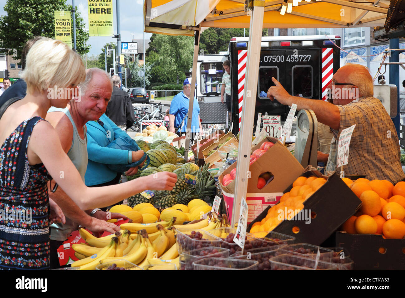 Persone che acquistano frutta e verdura da uno stallo in Portsmouth street market England Regno Unito Foto Stock