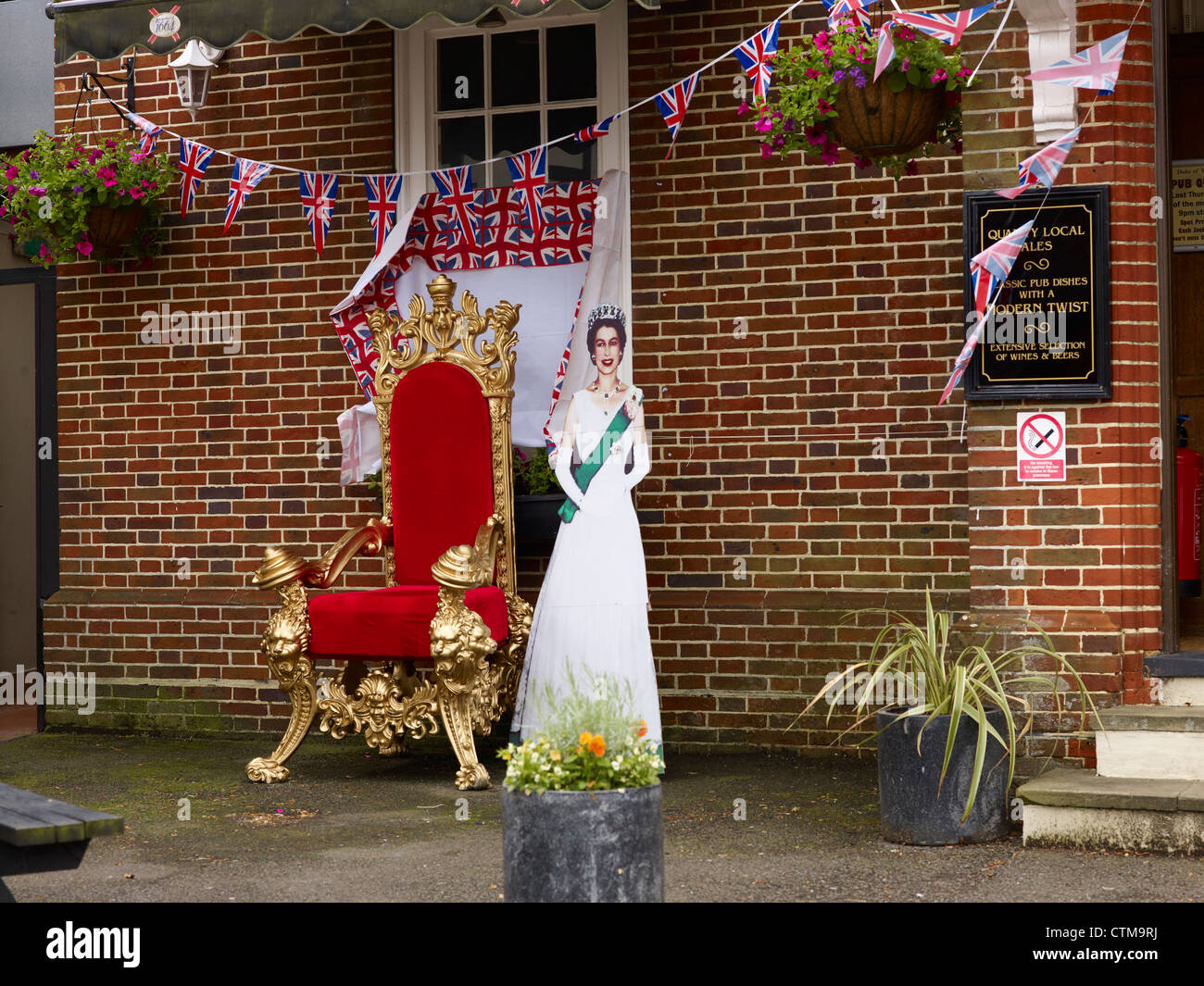 Ritaglio di cartone della regina di rosso e un trono al di fuori di una casa pubblica sulla regina del Giubileo di Diamante Foto Stock