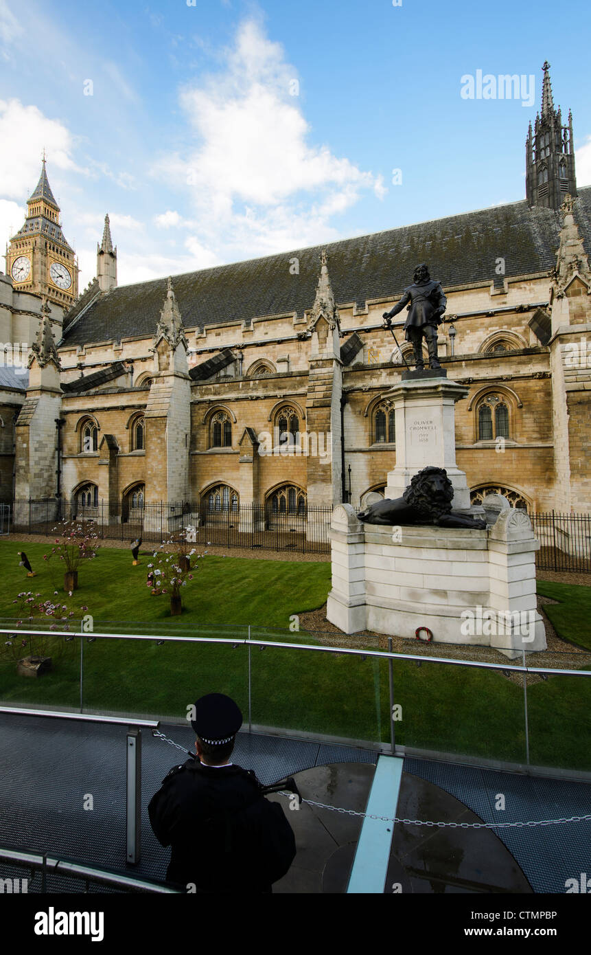 Un poliziotto di guardia di fronte di Oliver Cromwell statua presso il Palazzo di Westminster Foto Stock